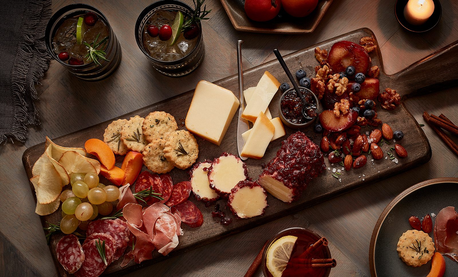 A fall inspired charcuterie board filled with slices naturally aged cheddar, cheddar logs, almonds, raspberries, blueberries, variety of sliced meats, grapes and biscuits.